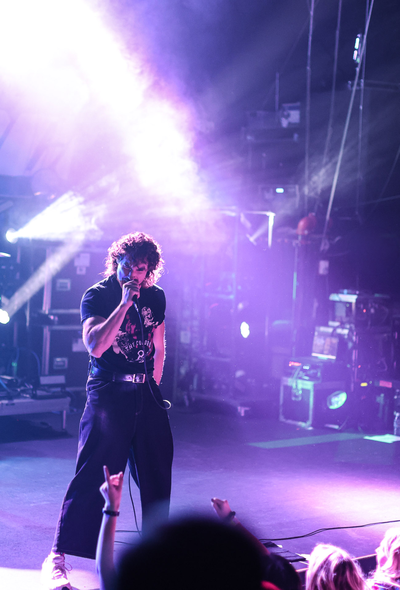 Rob Damani of Don Broco singing into a microphone on stage under pink lighting, performing to a lively crowd.