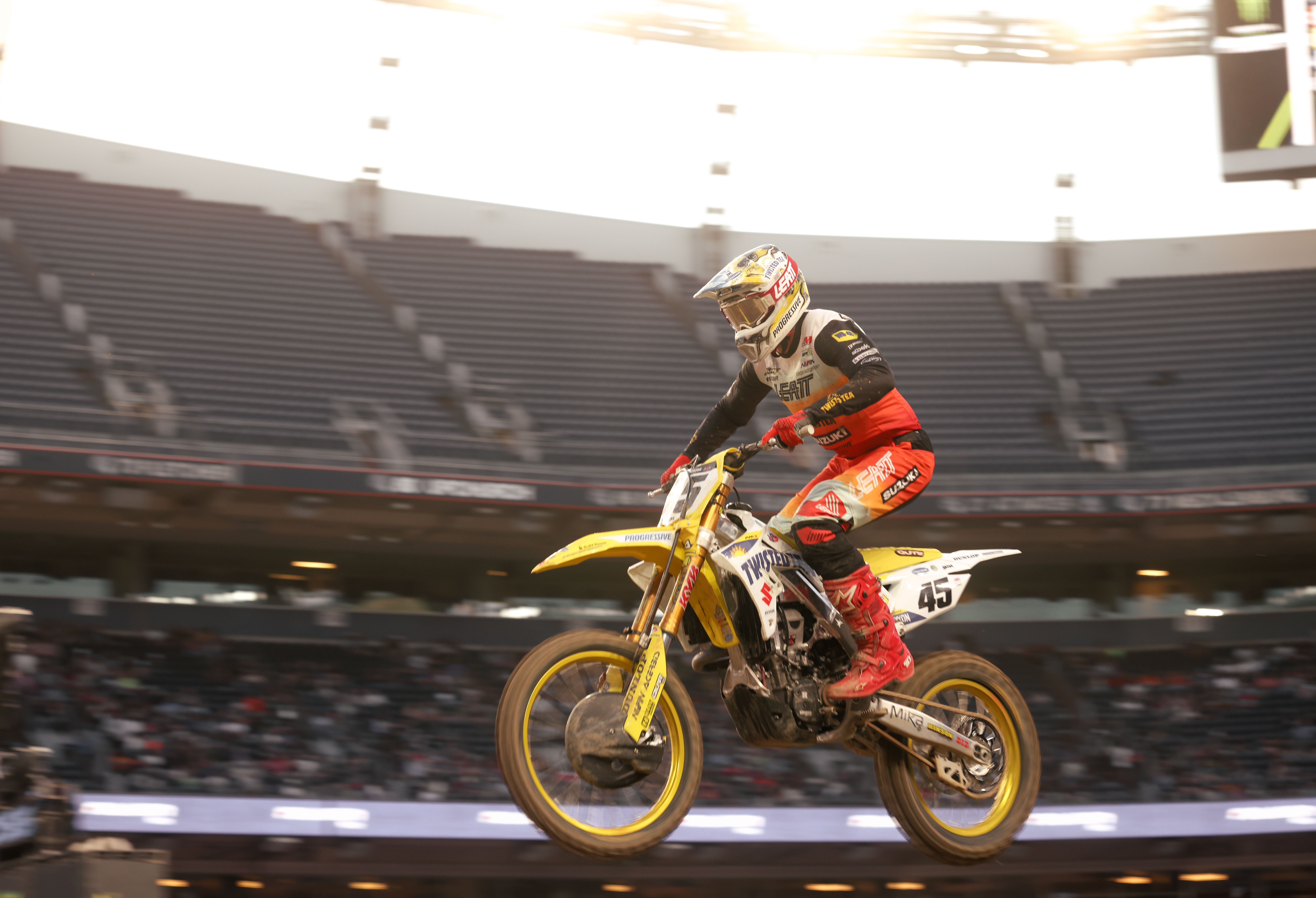 Colt Nichols number 45 mid-air on his Suzuki under bright stadium lights.