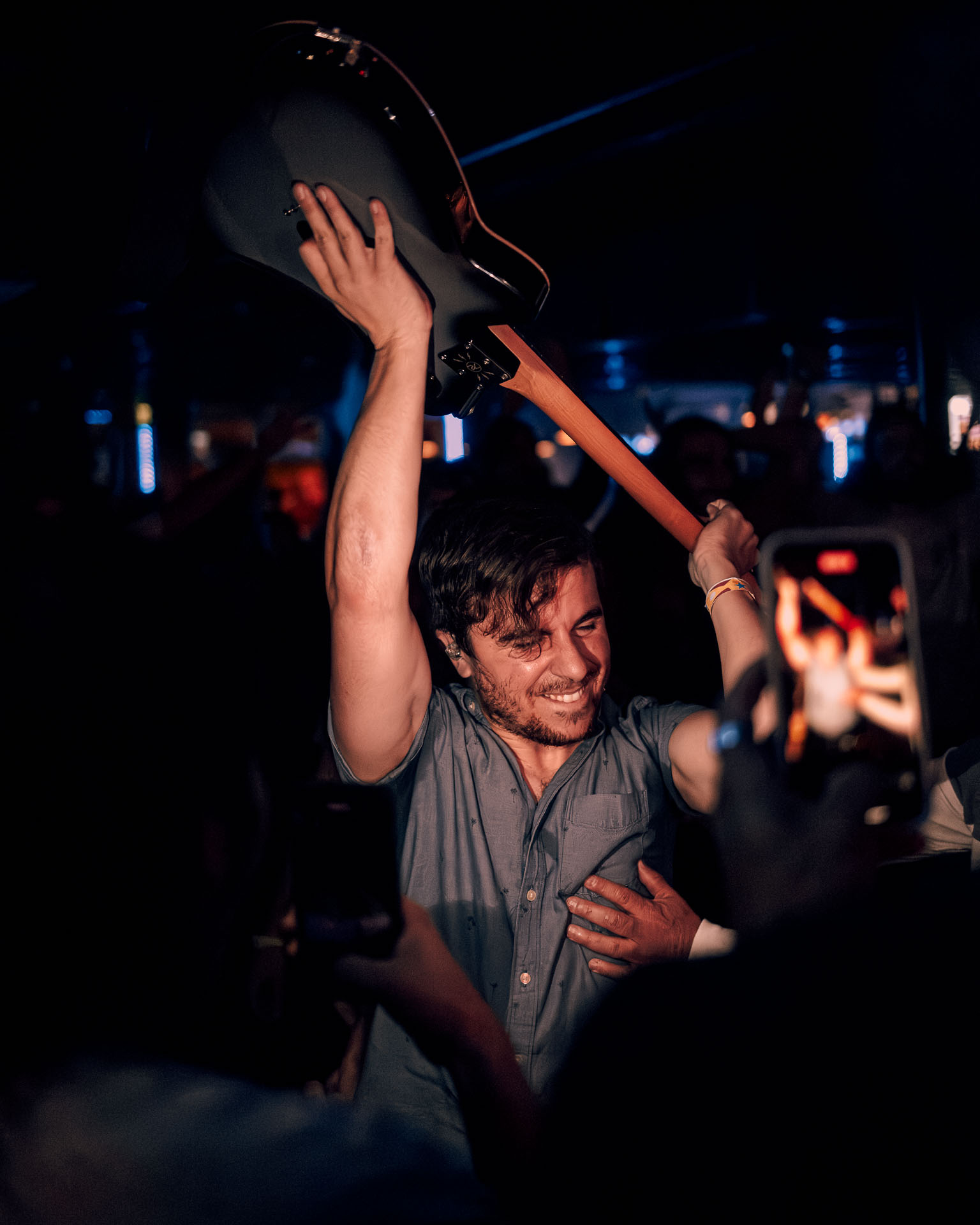 Greg Almeida, guitarist of A Lot Like Birds, smiling, holding guitar in crowd of Denver, Co