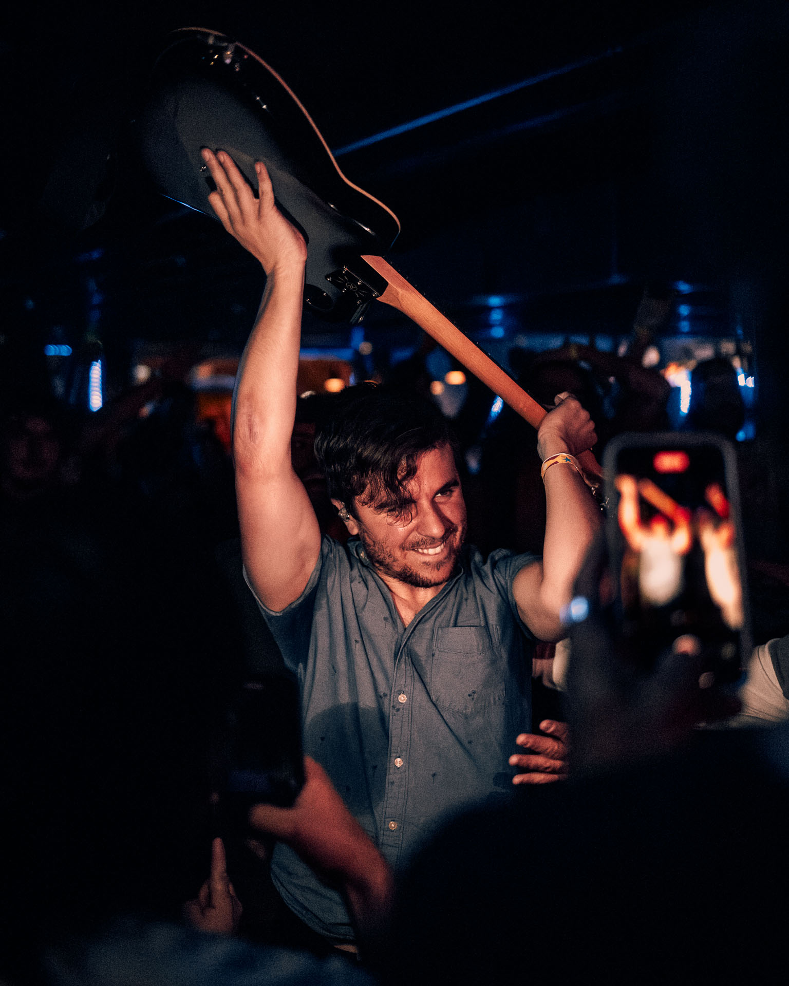 Greg Almeida, guitarist of A Lot Like Birds, smiling, holding guitar in crowd of Denver, Co