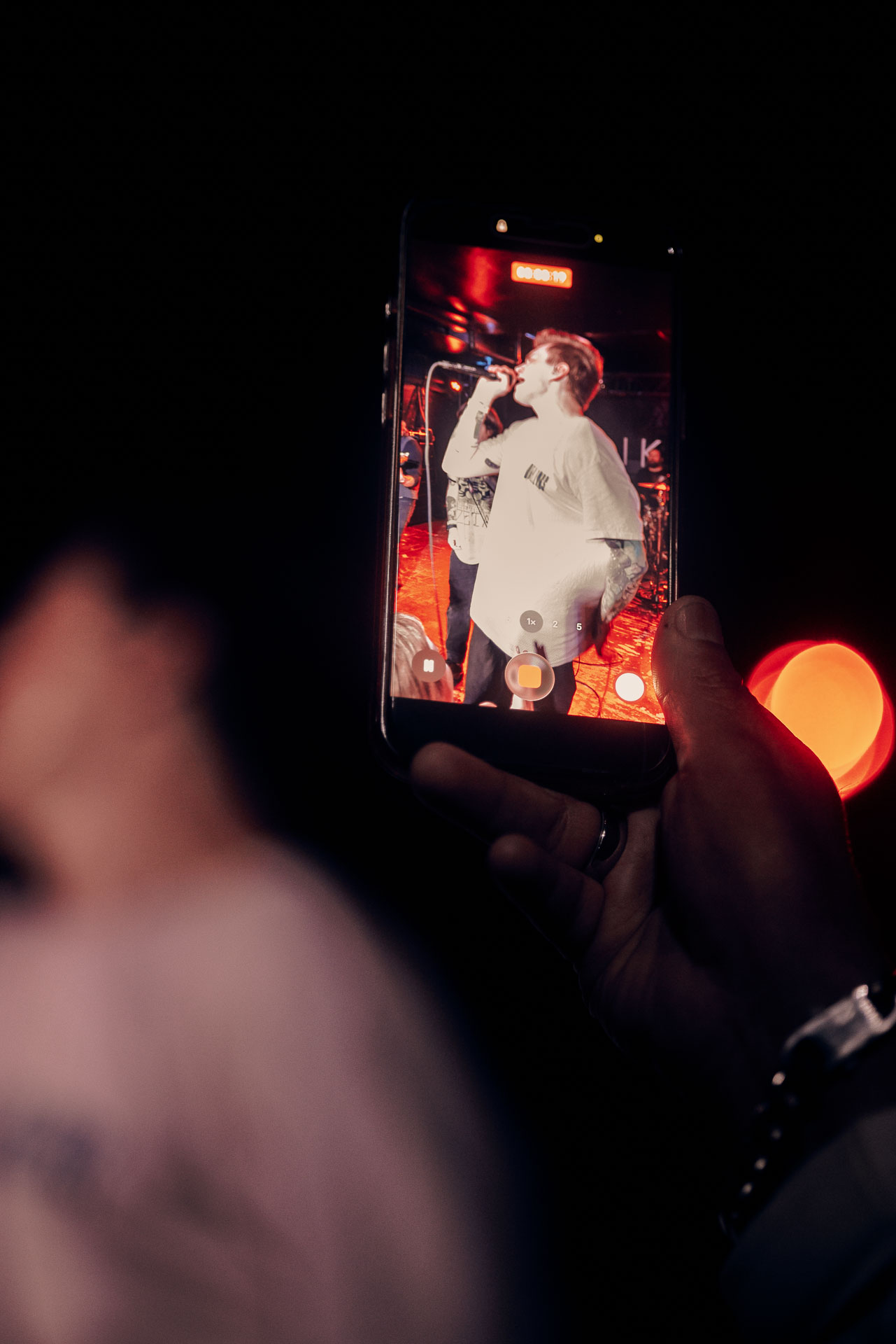 Fan holding up phone to record Andy Cizek performing during A Lot Like Birds concert at HQ in Denver, Colorado, USA