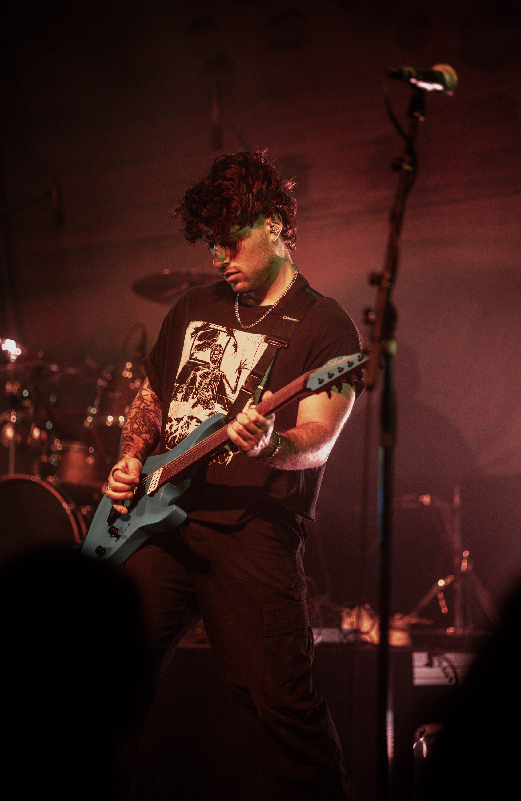 Belmont guitarist playing under stage lights during a live performance in Denver, Colorado.