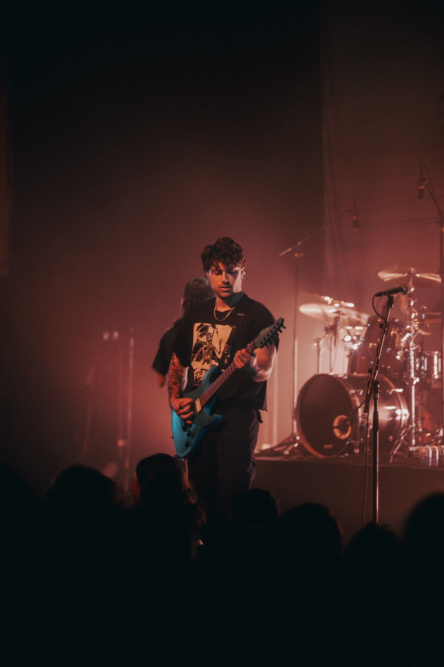Belmont guitarist playing under stage lights during a live performance in Denver, Colorado.